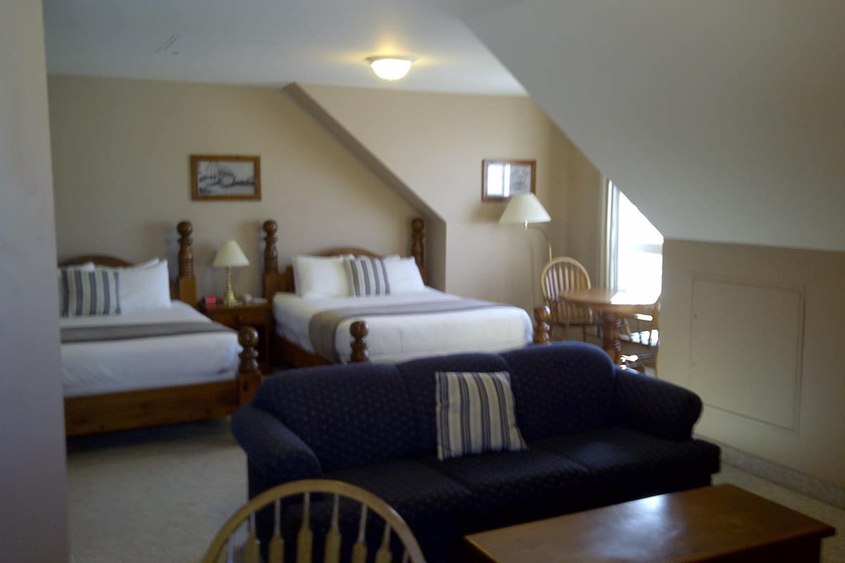 Une chambre d’hôtel avec deux lits, un canapé, une chaise et une petite table.