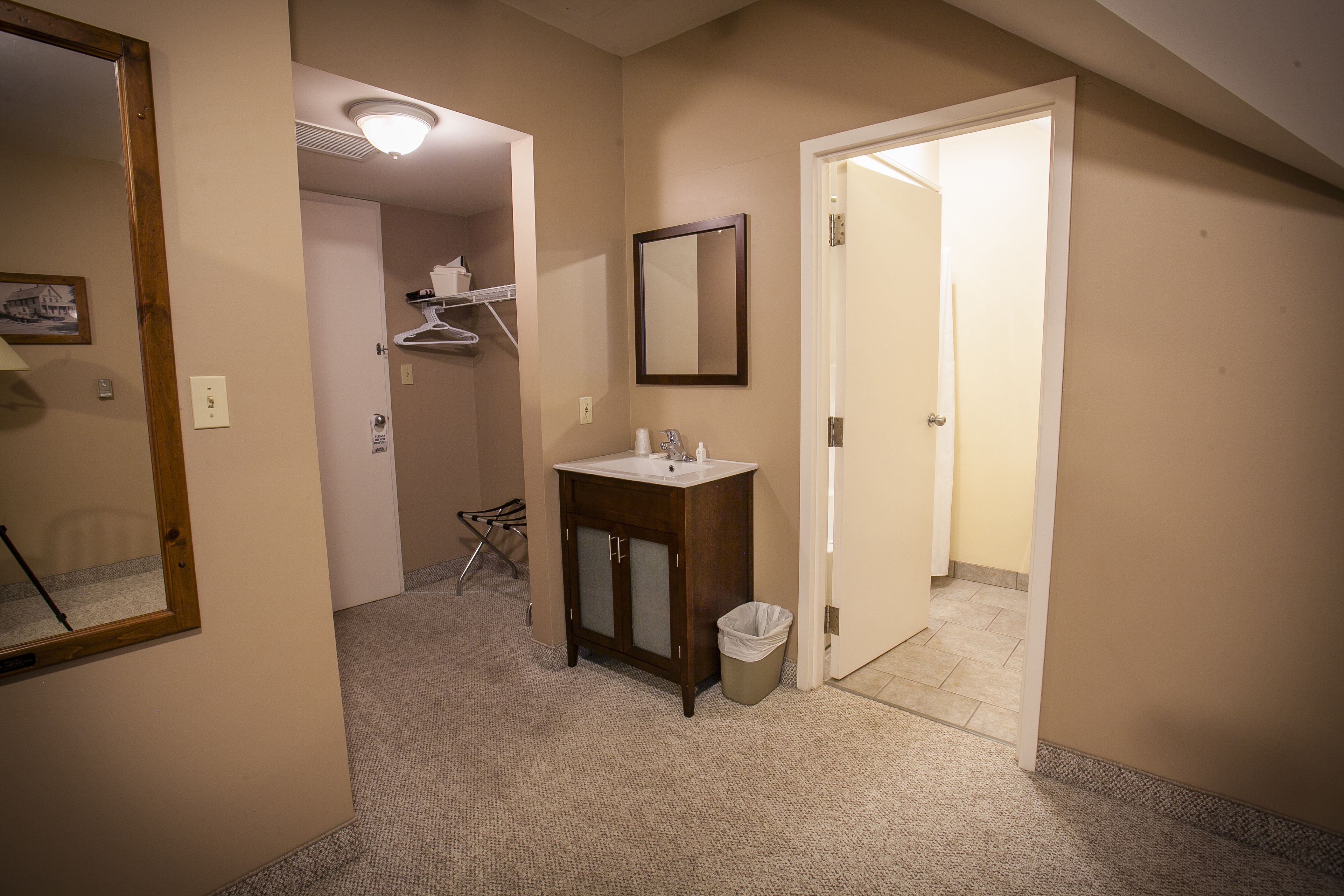 A hotel bathroom with a sink, mirror, and a trash bin.