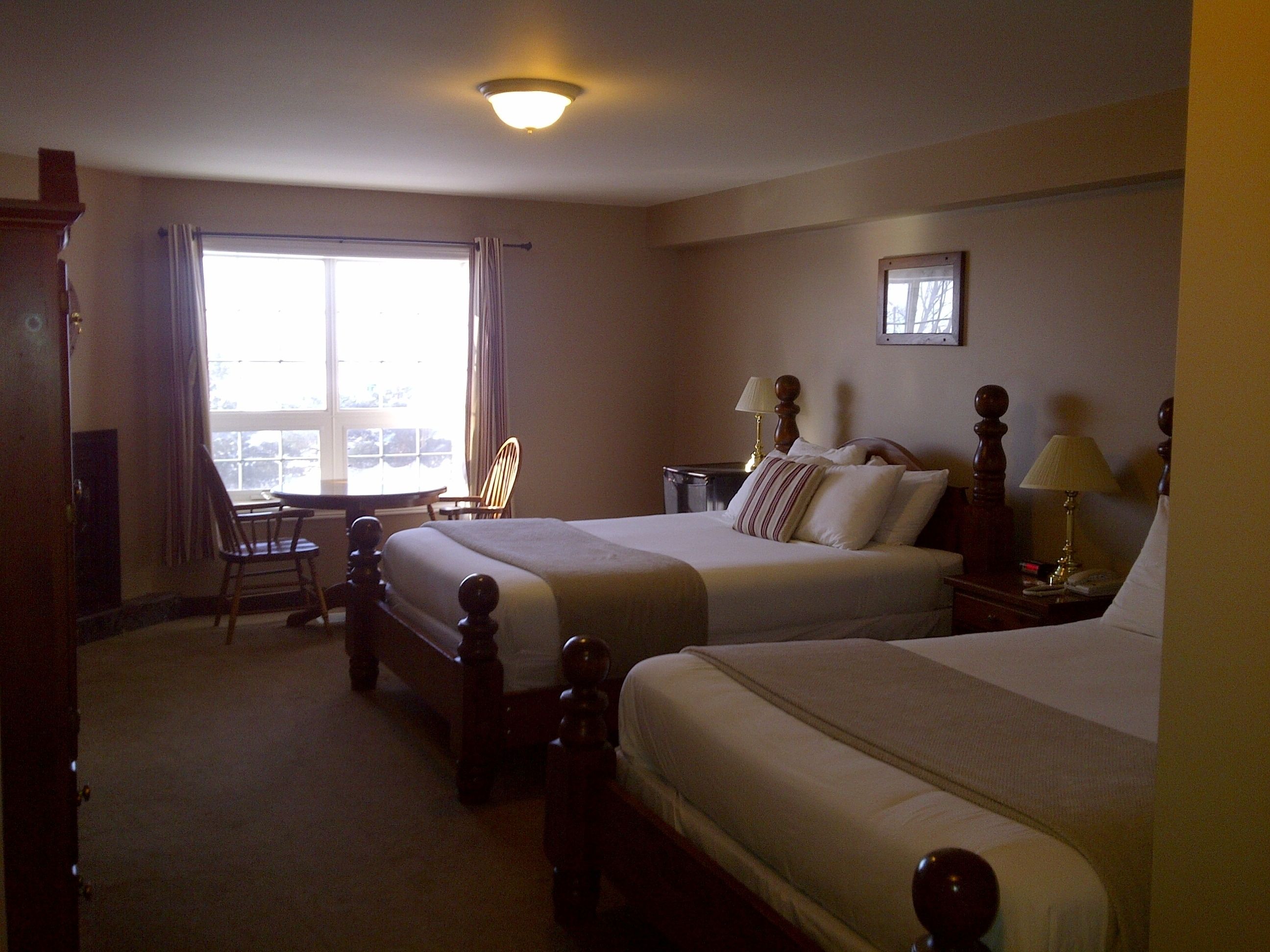 A hotel room with two beds, a desk, and a chair.