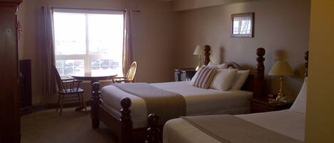 A hotel room with two beds, a desk, and a chair.
