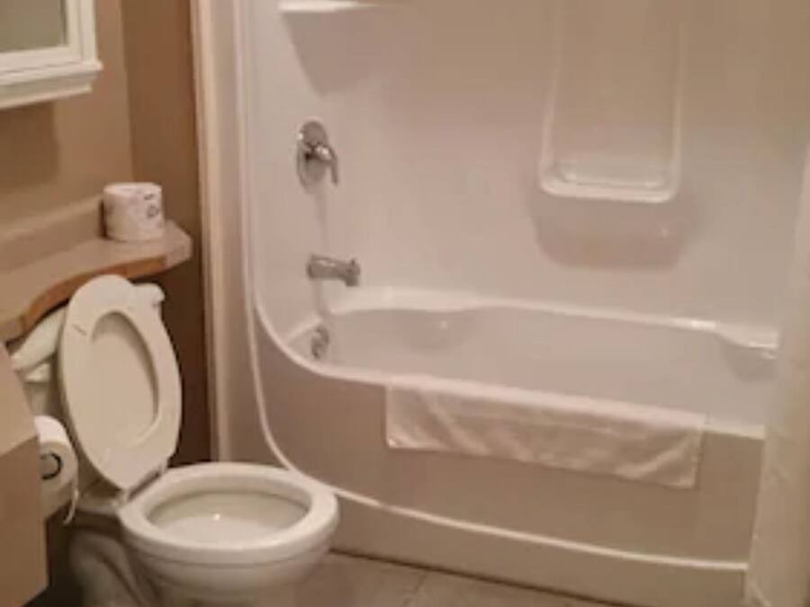 A bathroom with a toilet, a bathtub, and a shower area.