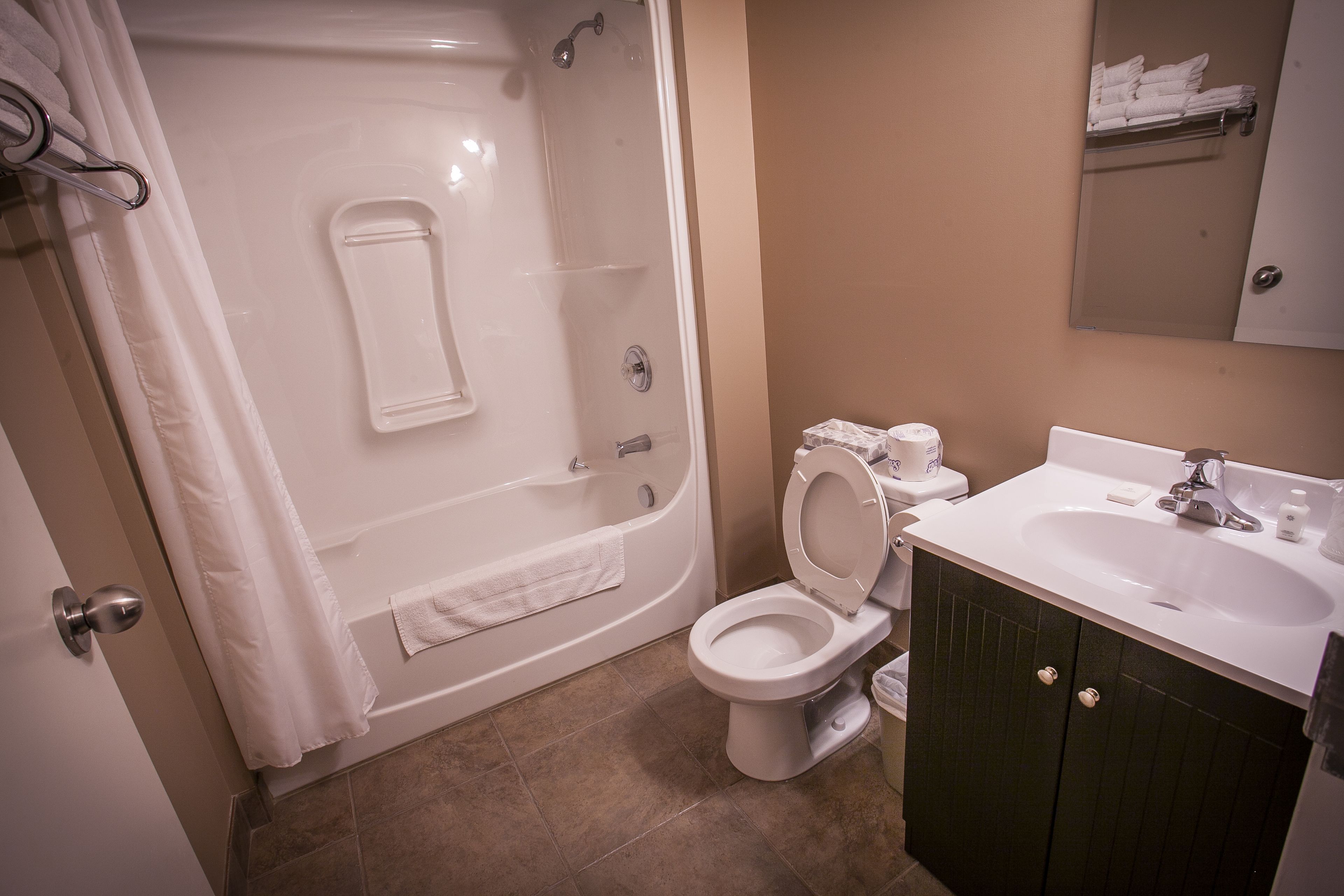 A bathroom with a bathtub, toilet, sink, and a mirror.