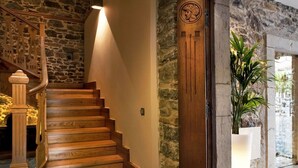 Una escalera de madera con paredes de piedra y una puerta decorativa.