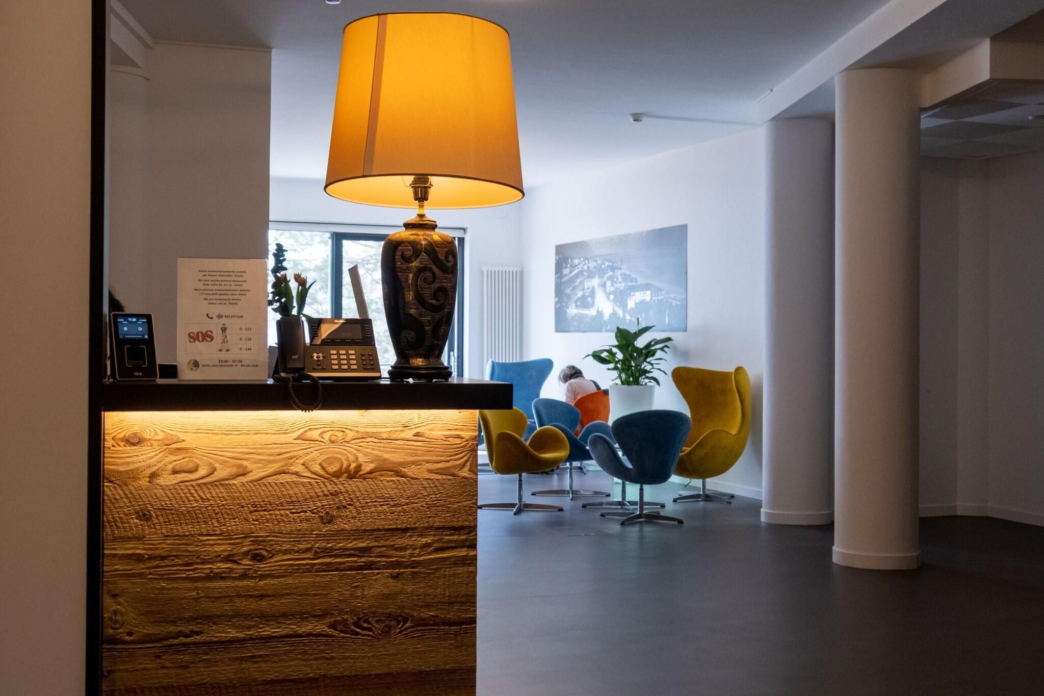 Un área de recepción con un mostrador de madera, una lámpara grande y sillas coloridas.