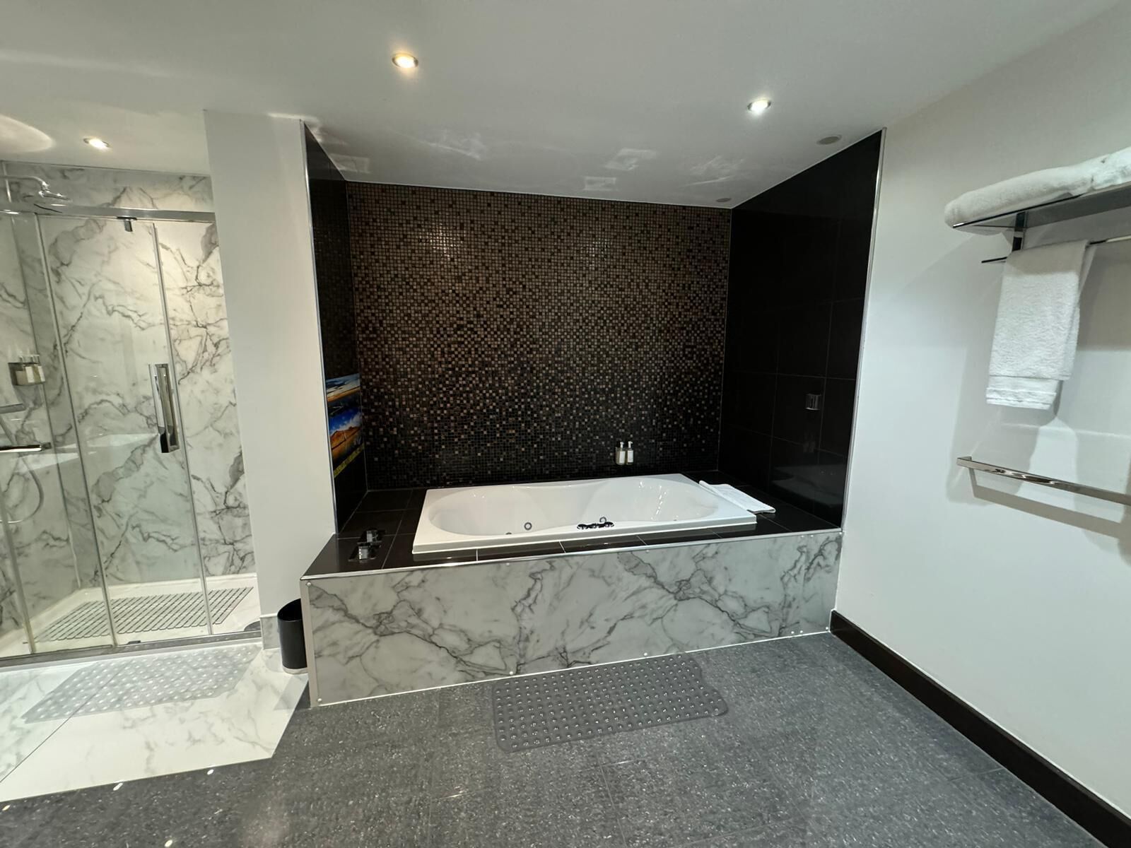 A modern bathroom with a large bathtub, a shower area, and a tiled wall.