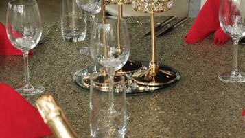 A table set with wine glasses, a champagne bottle, and a decorative centerpiece with flowers and crystals.