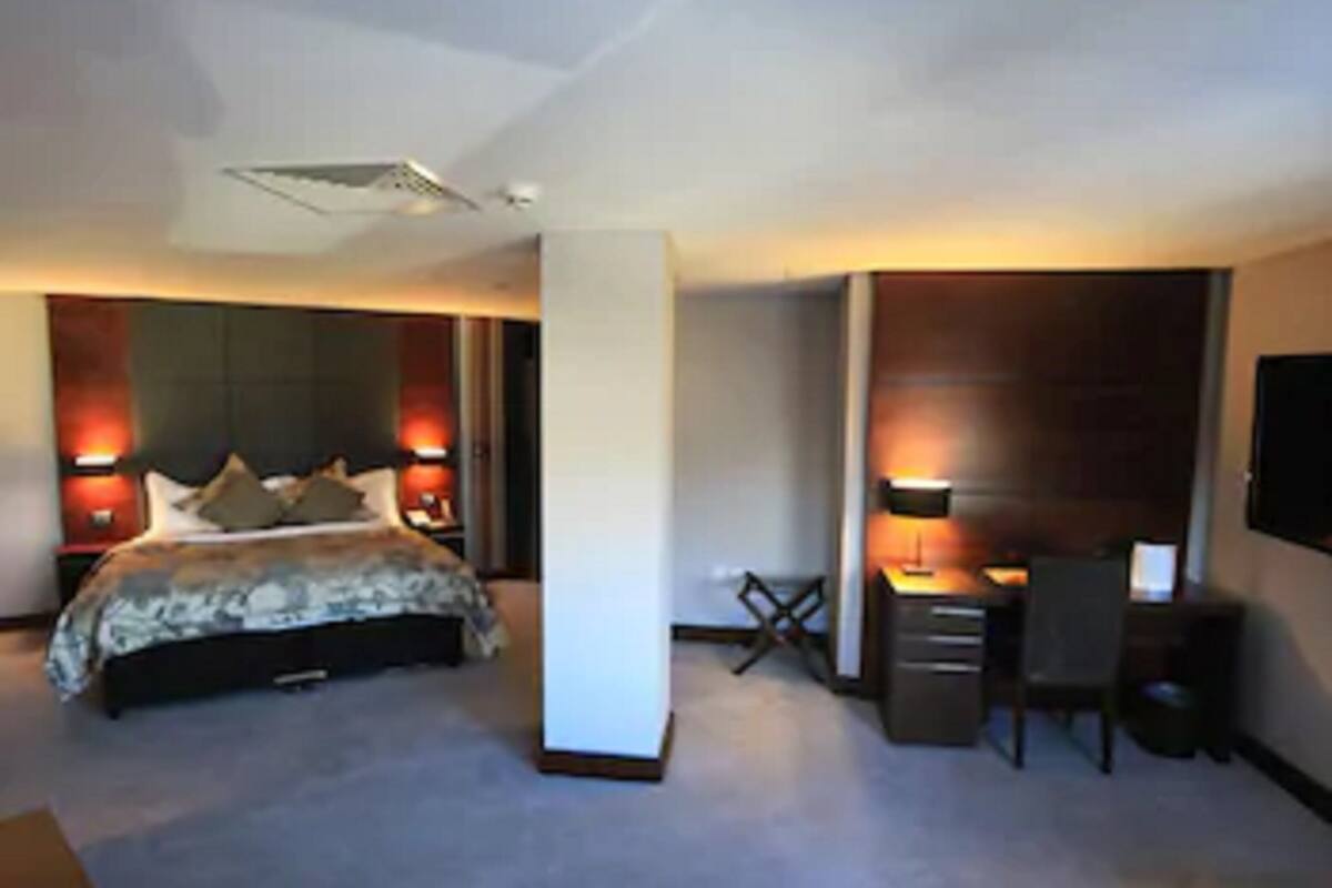 A hotel room with a bed, desk, chair, and TV.