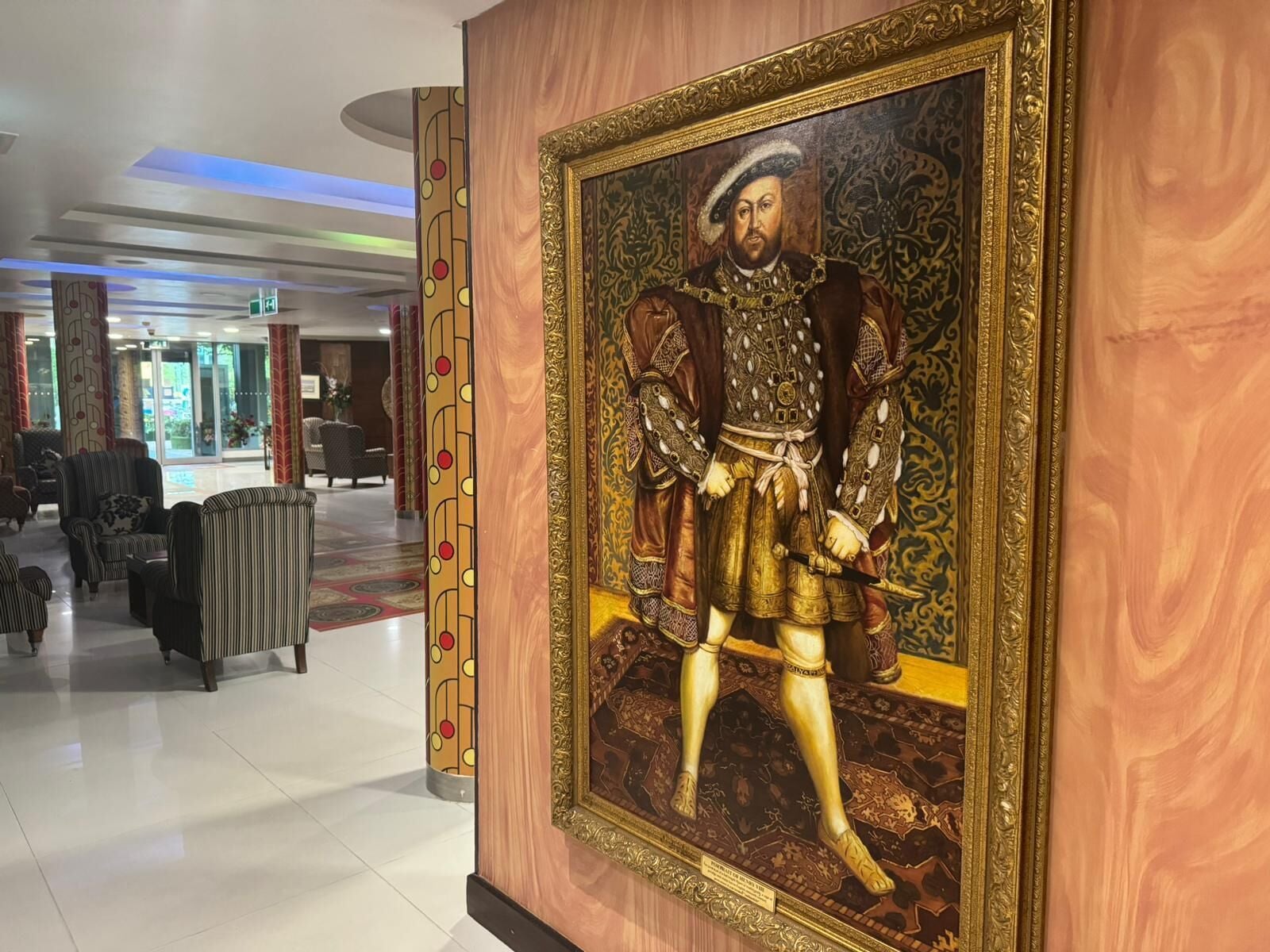 A lobby with a large portrait of a historical figure, seating areas, and a modern ceiling design.