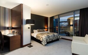 A modern hotel room with a large bed, a desk, and a laptop.