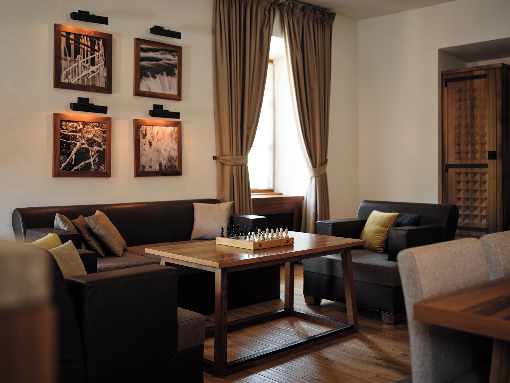 A modern living room with a wooden coffee table, a sofa, and a chessboard.