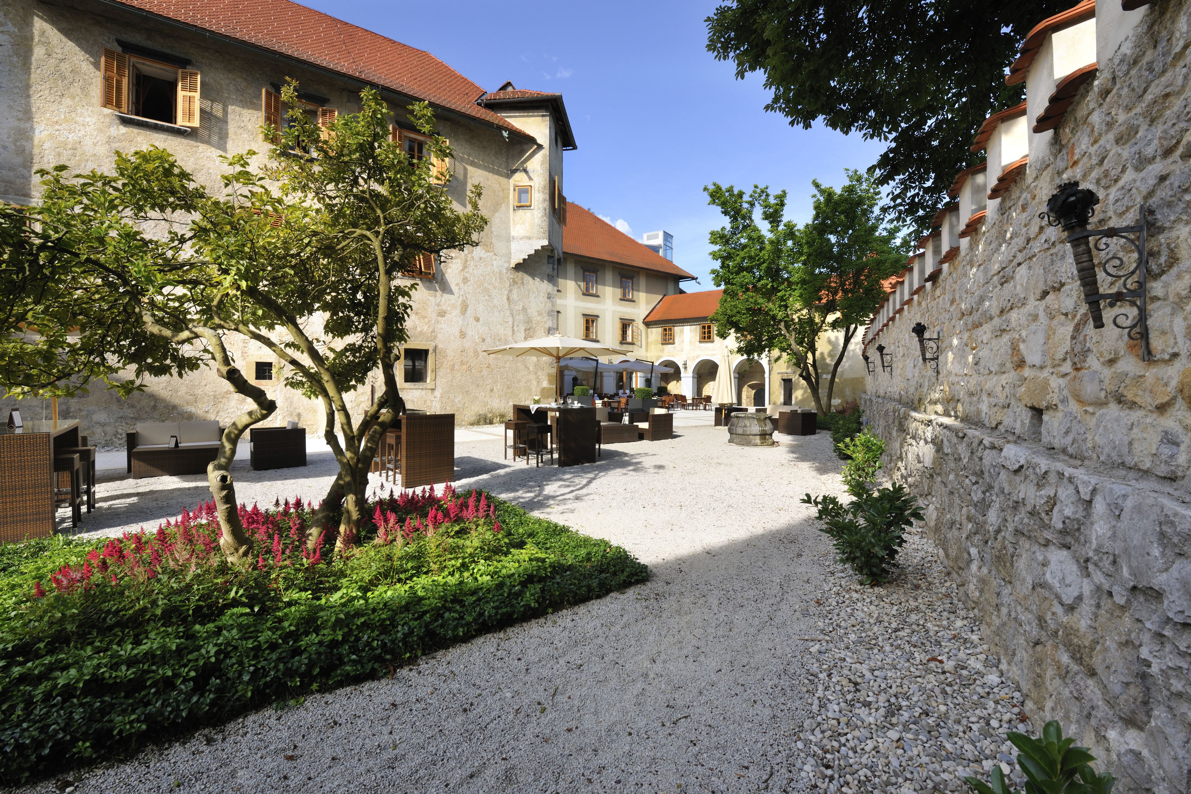 A courtyard with outdoor seating, a gravel path, and stone walls.