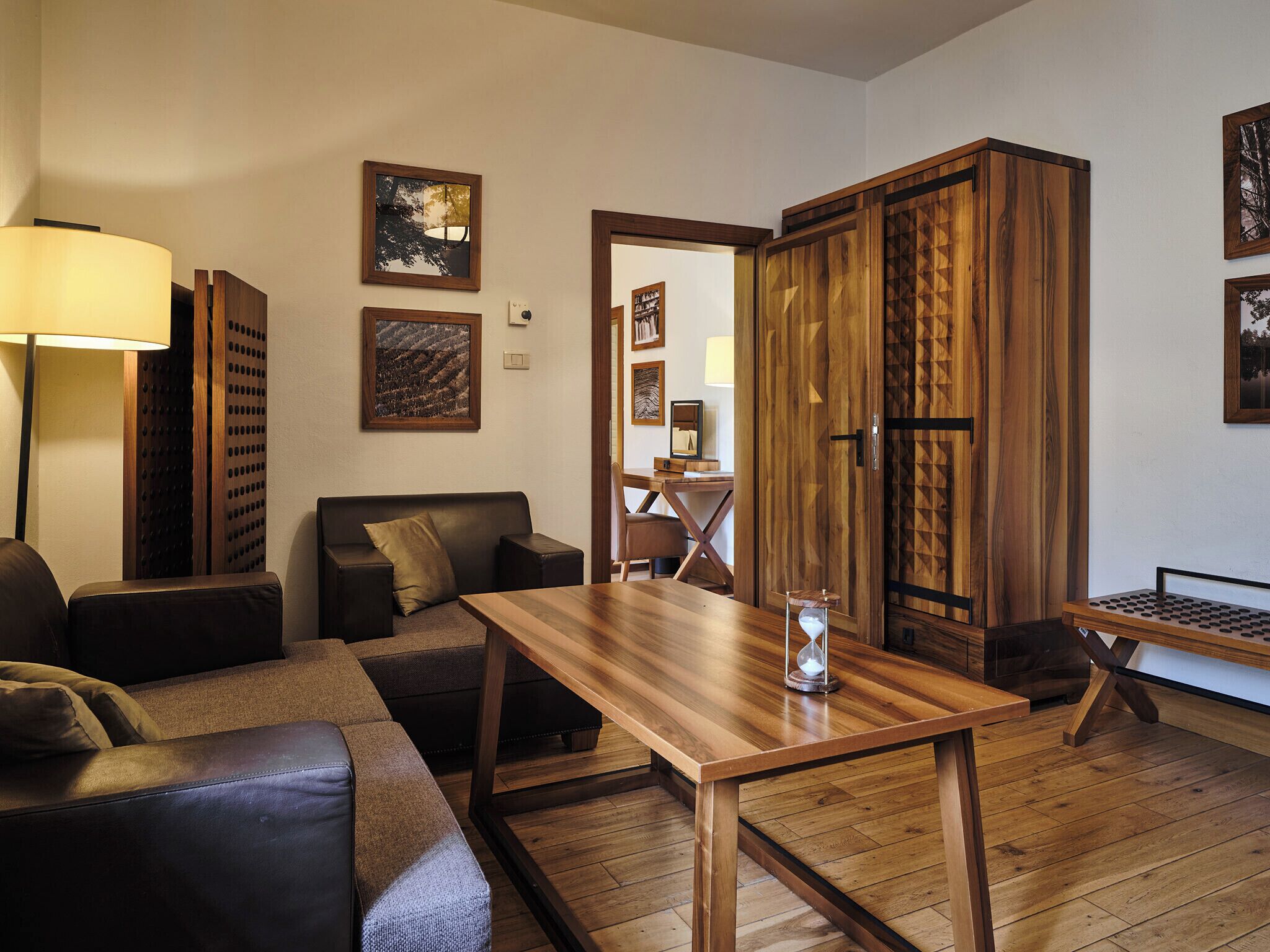A modern living room with a wooden table, leather sofa, and a wooden cabinet.