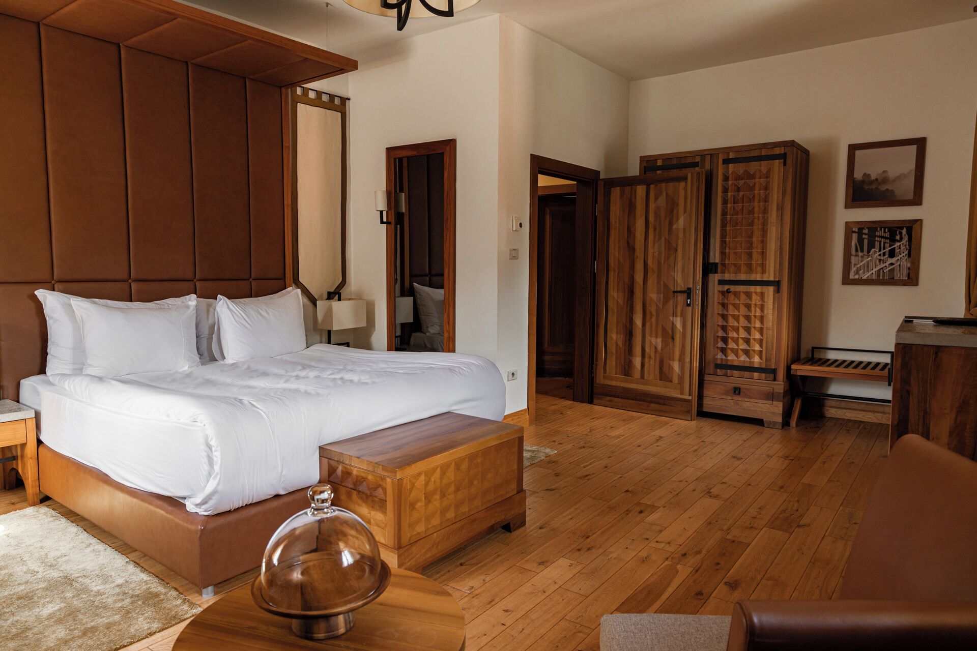 Een hotelkamer met een groot bed, een houten garderobe en een bureau met een lamp.