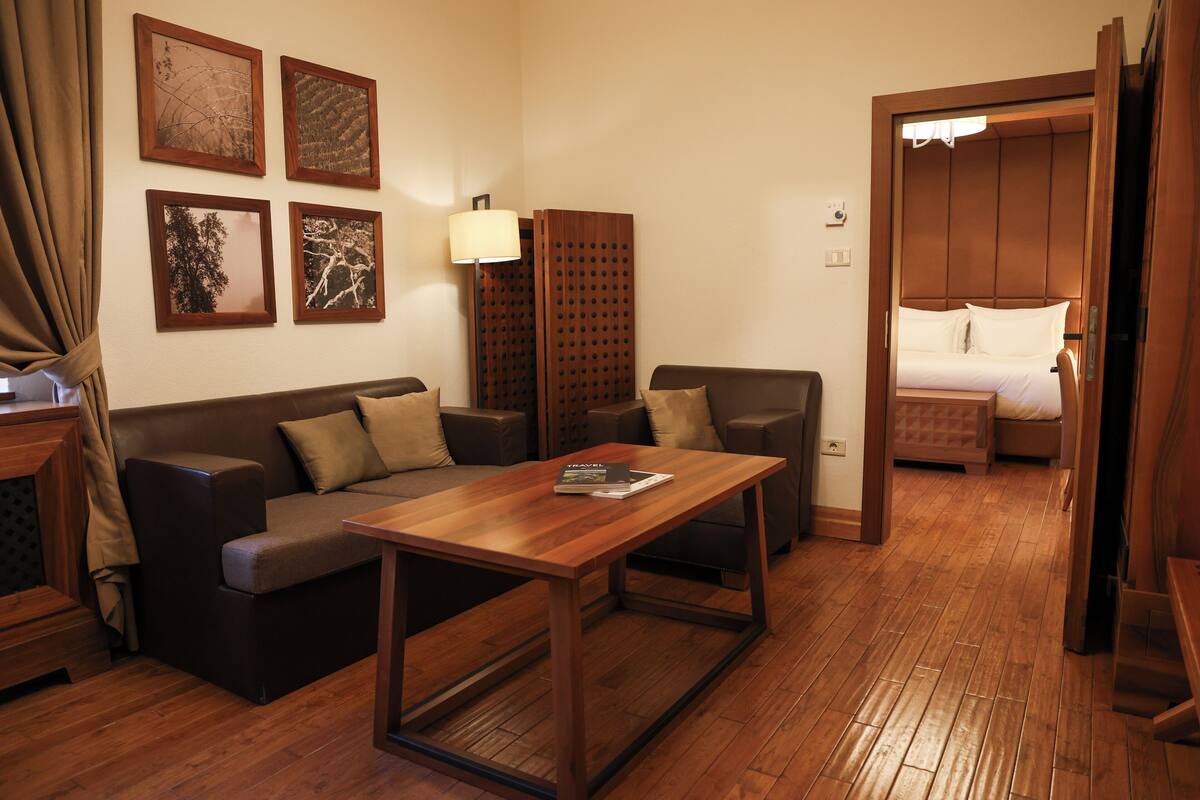 Ein Hotelzimmer mit Holzboden, einer Couch, einem Tisch, einem Bett und einer Holzwand.