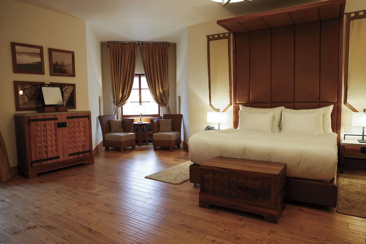 Ein geräumiges Schlafzimmer mit einem großen Bett, einem Holzkopfende und einem Holzschrank mit Fernseher.