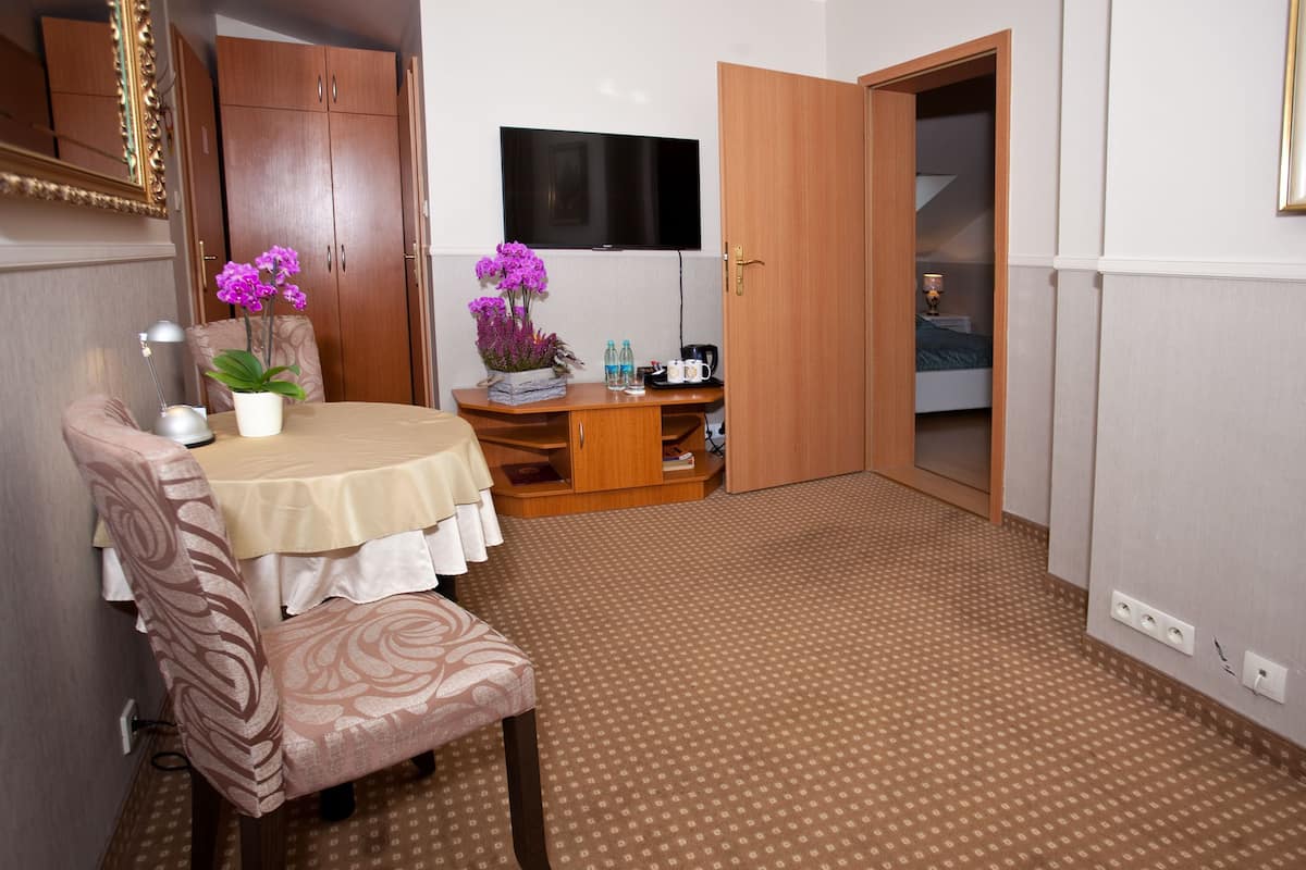 Quarto compacto com escrivaninha de madeira, uma cadeira, televisão e guarda-roupa.