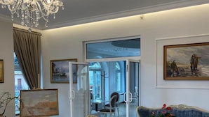 A spacious room with a chandelier, a painting, a sofa, and a table with a plant. - Moris Boutique Beach Hotel (Gdansk)