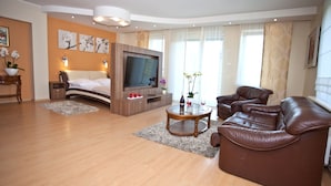 A modern living room with a large flat-screen TV, leather sofa, and a wooden coffee table. - Moris Boutique Beach Hotel (Gdansk)