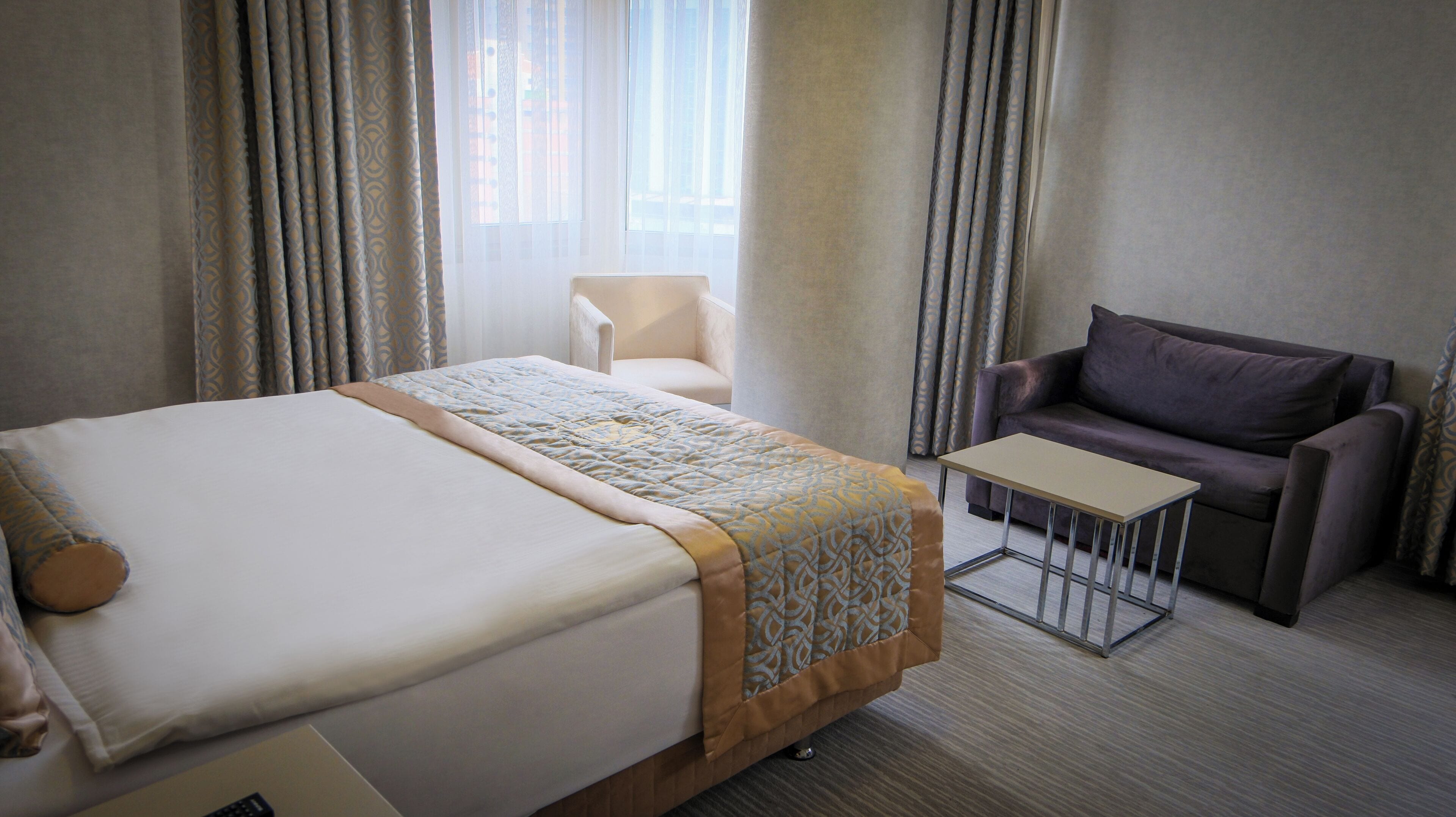 Una habitación de hotel con cama, una mesita, un sofá y una silla.