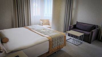 Una habitación de hotel con cama, una mesita, un sofá y una silla.