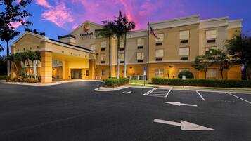 Hotel Comfort Suites con cielo despejado y estacionamiento al frente.
