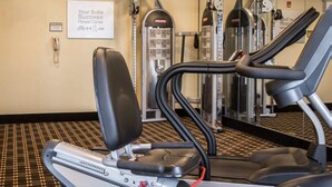 Een fitnessruimte met loopbanden, krachttrainingsapparaten en een bord waarop staat 'Suite Success Fitness Center'.