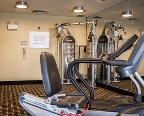 Une salle de sport équipée de tapis de course, d’appareils de musculation et d’une enseigne indiquant qu’il s’agit d’une salle de sport de premier ordre.