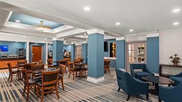 A hotel lobby with multiple seating areas, a reception desk, and a bar.