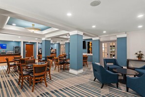 Een hotel lobby met meerdere zithoeken, een receptiebalie en een bar.