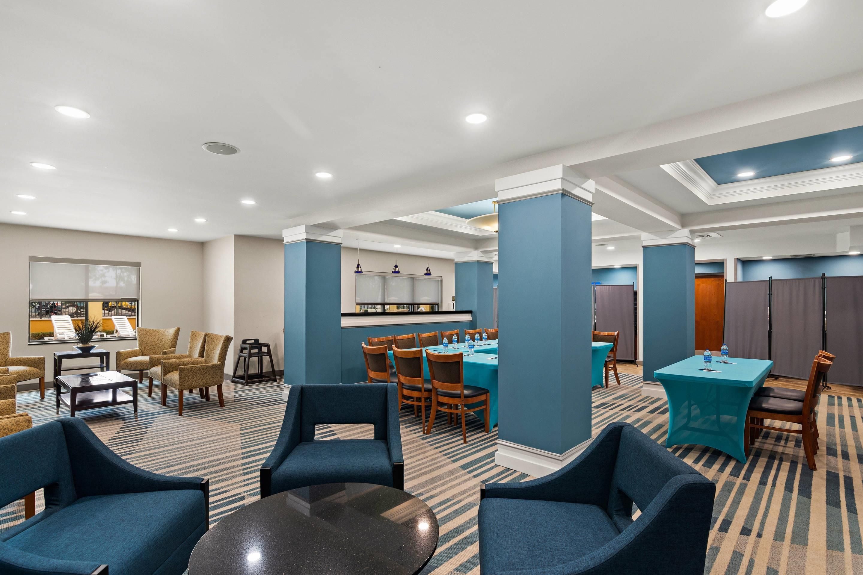 Un vestíbulo de hotel con zonas de estar, una recepción y un comedor.