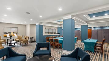Un vestíbulo de hotel con zonas de estar, una recepción y un comedor.