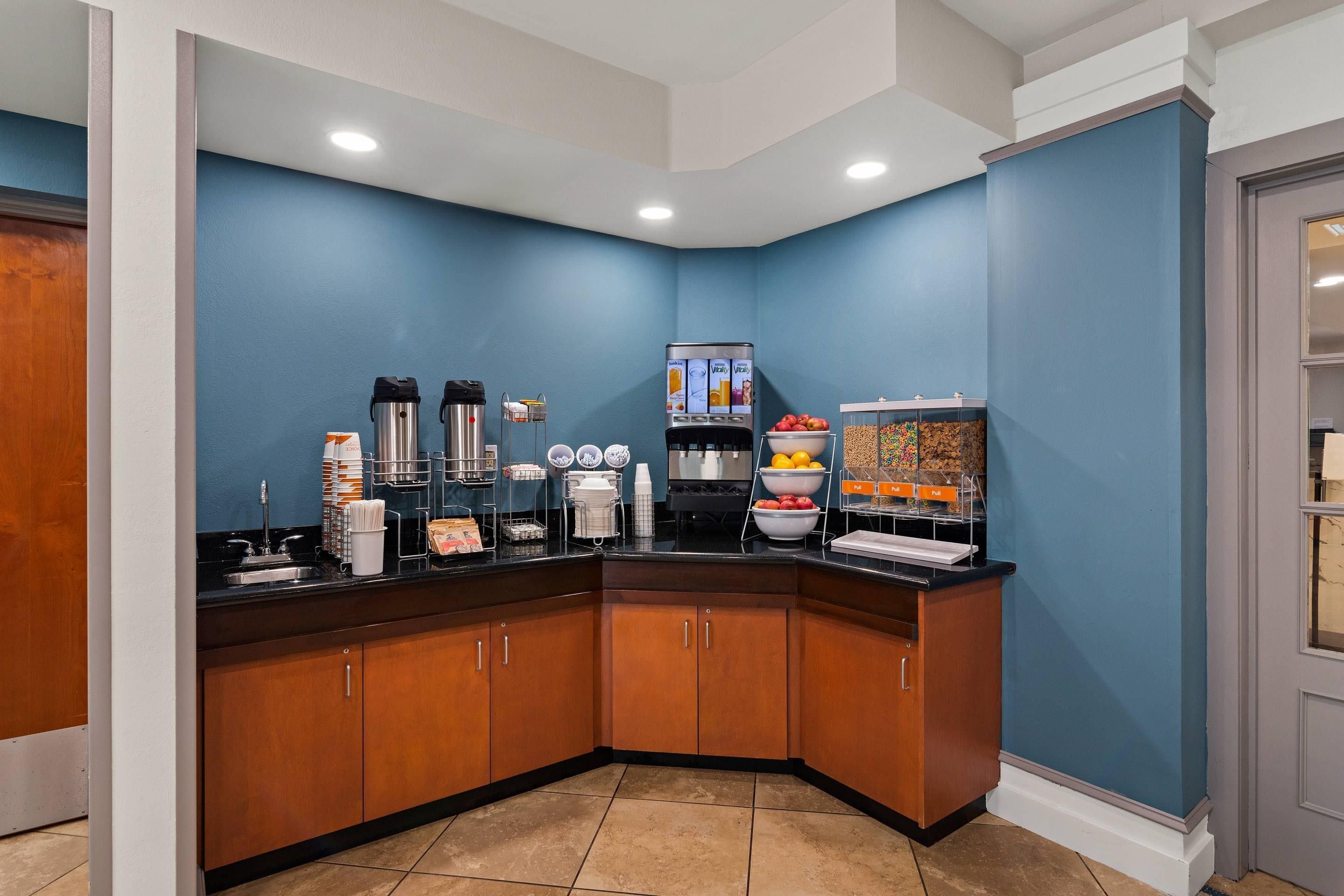 A corner kitchenette with a coffee station, a fruit bowl, and a cereal bar.