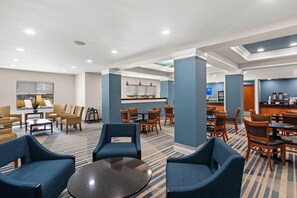 A hotel lobby with seating areas, a reception desk, and a coffee station.