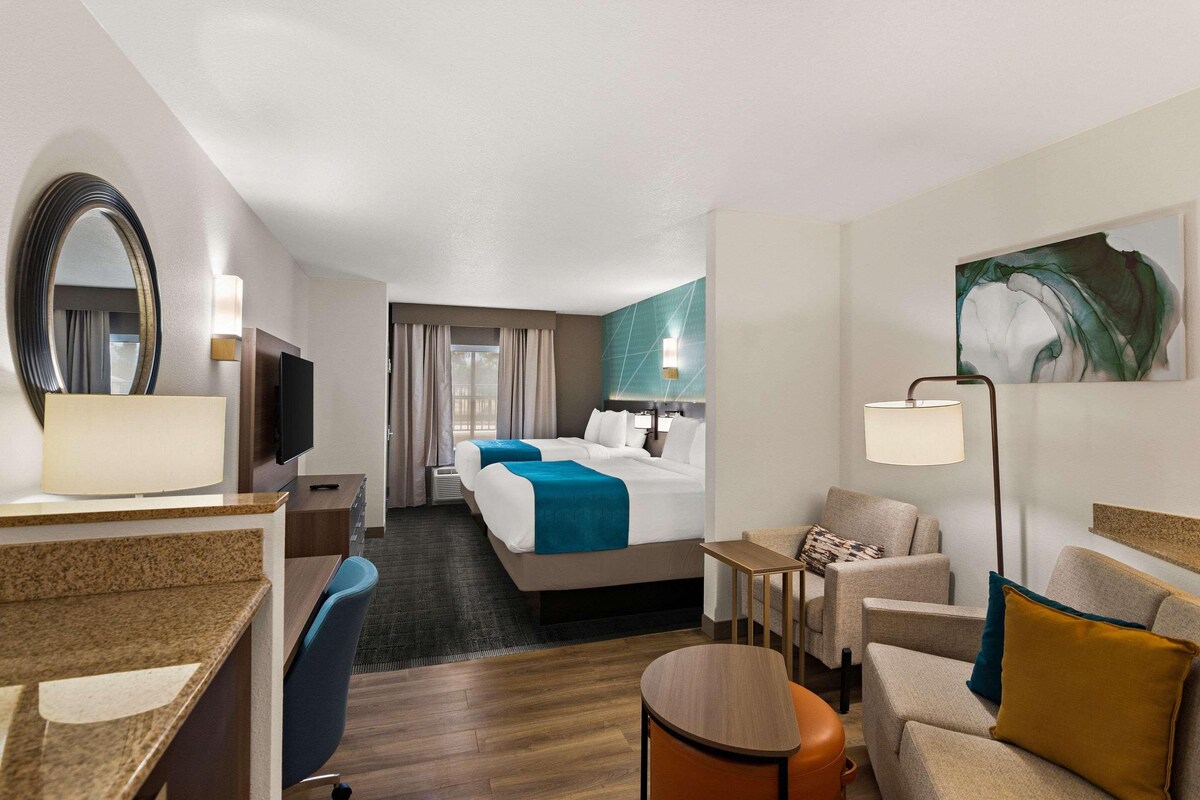 Ein Hotelzimmer mit einem Bett, einem Schreibtisch, einem Stuhl, einem kleinen Tisch und einem Fernseher.