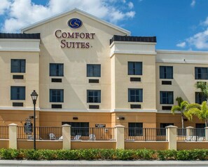 A hotel with a beige facade, multiple windows, and a sign reading "Comfort Suites."