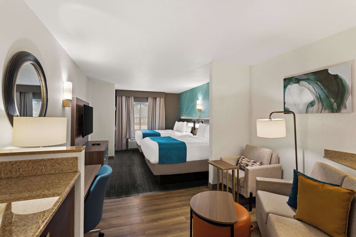 Ein Hotelzimmer mit Bett, Schreibtisch, Stuhl, kleinem Tisch und Fernseher.