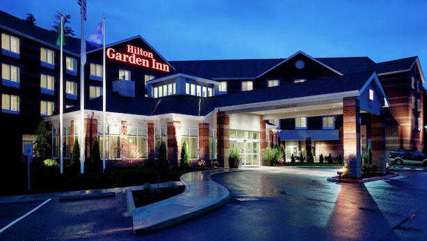 Ein Hilton Garden Inn mit großem Eingang, mehreren Etagen und einem Parkplatz.