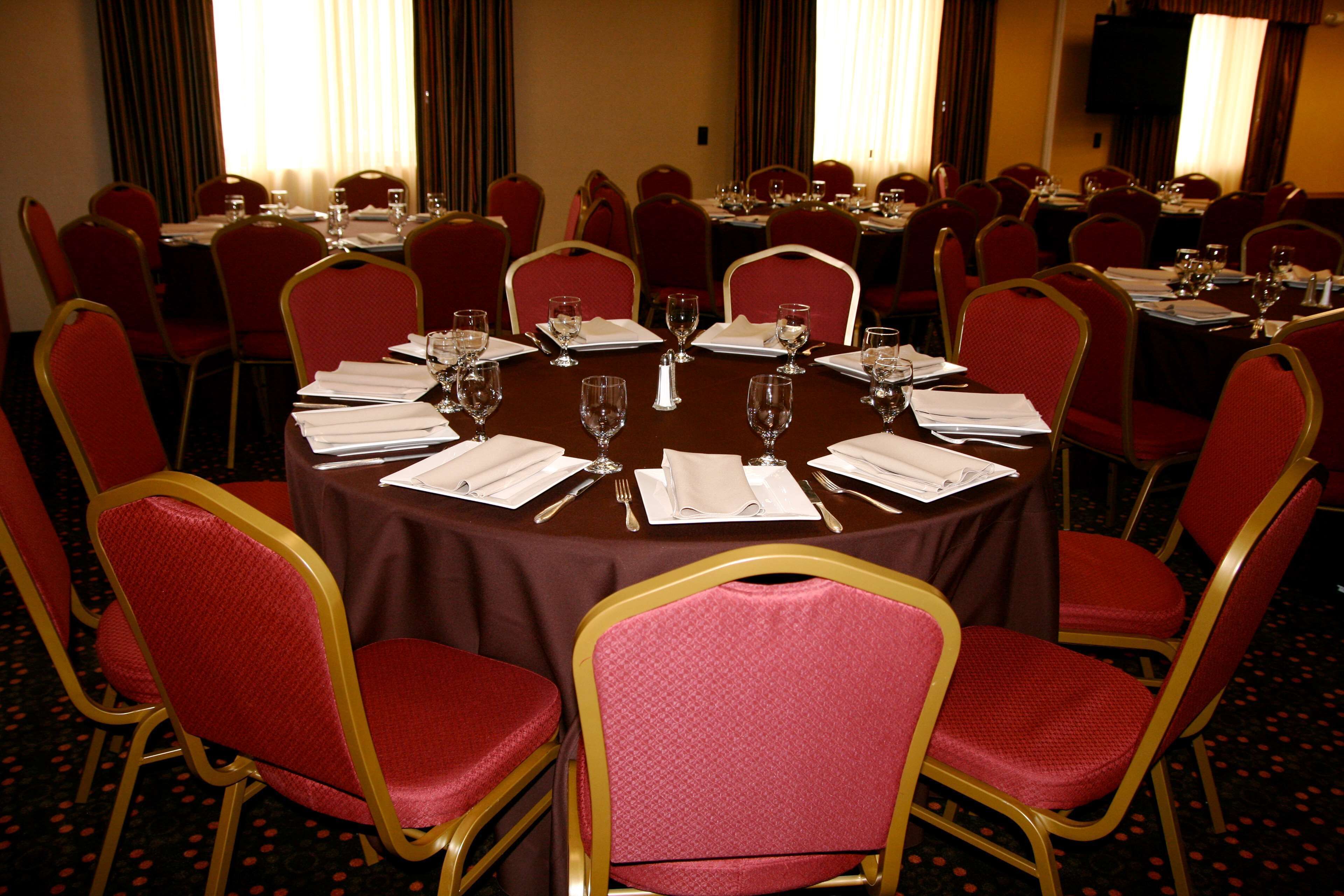 A conference room with round tables, red chairs, and a carpeted floor.