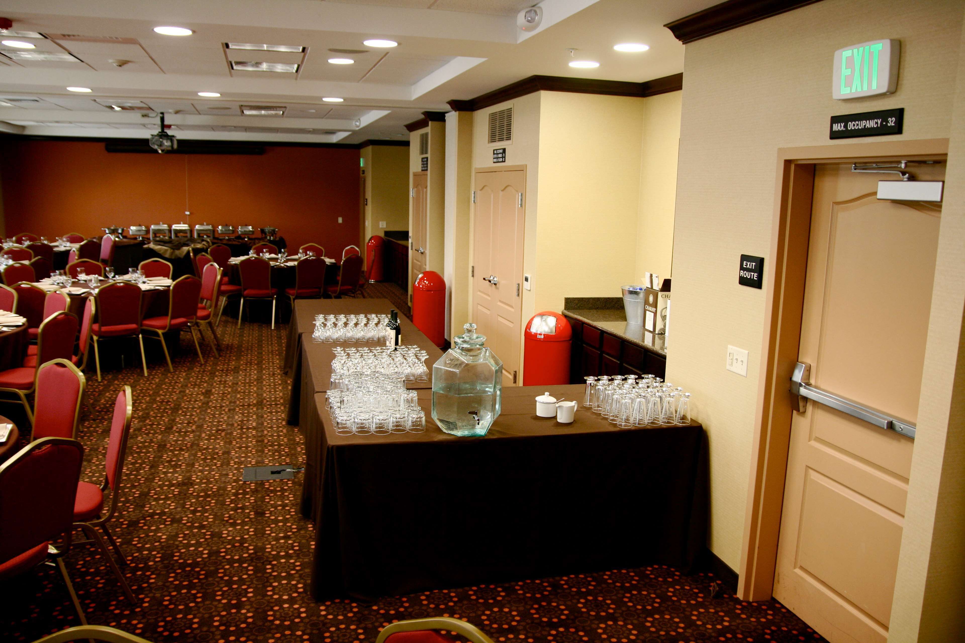 Une salle de conférence avec des tables disposées pour une réunion, équipée de chaises, d’un distributeur d’eau et d’un projecteur.