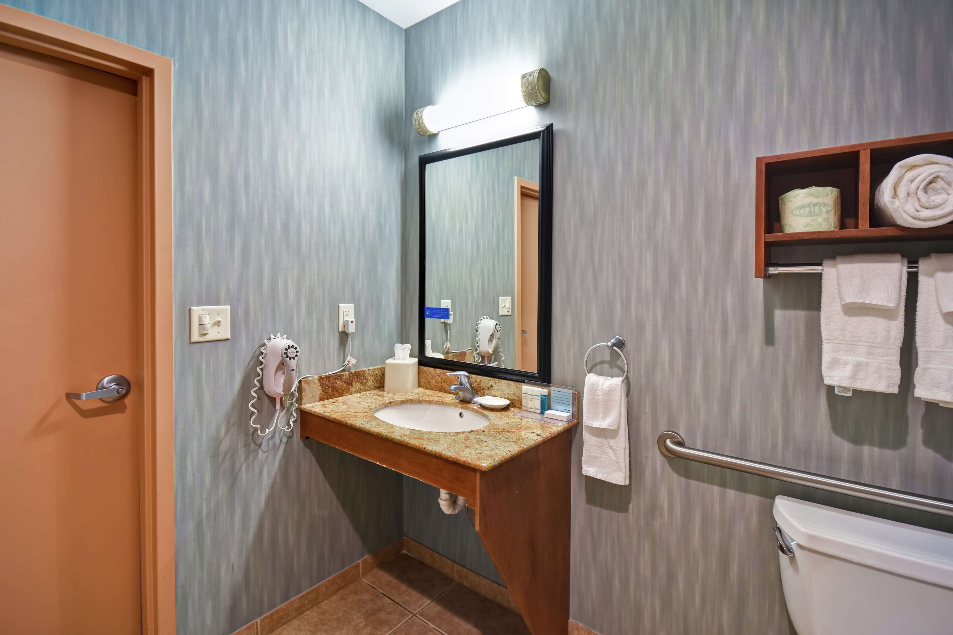 A bathroom with a sink, mirror, towel rack, and toilet.