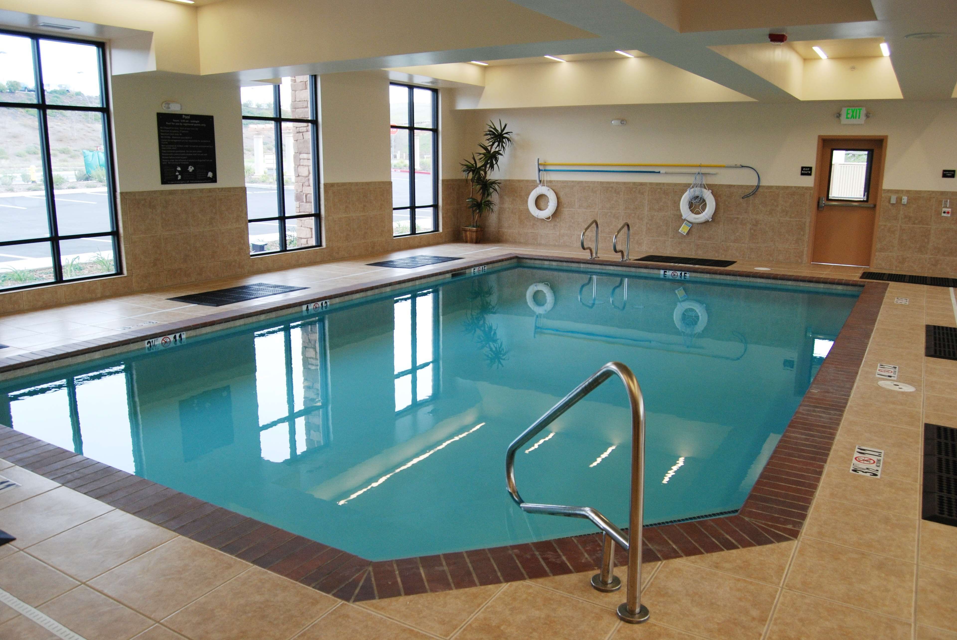 Una piscina coperta con acqua cristallina, una postazione per il bagnino e un cartello di sicurezza.