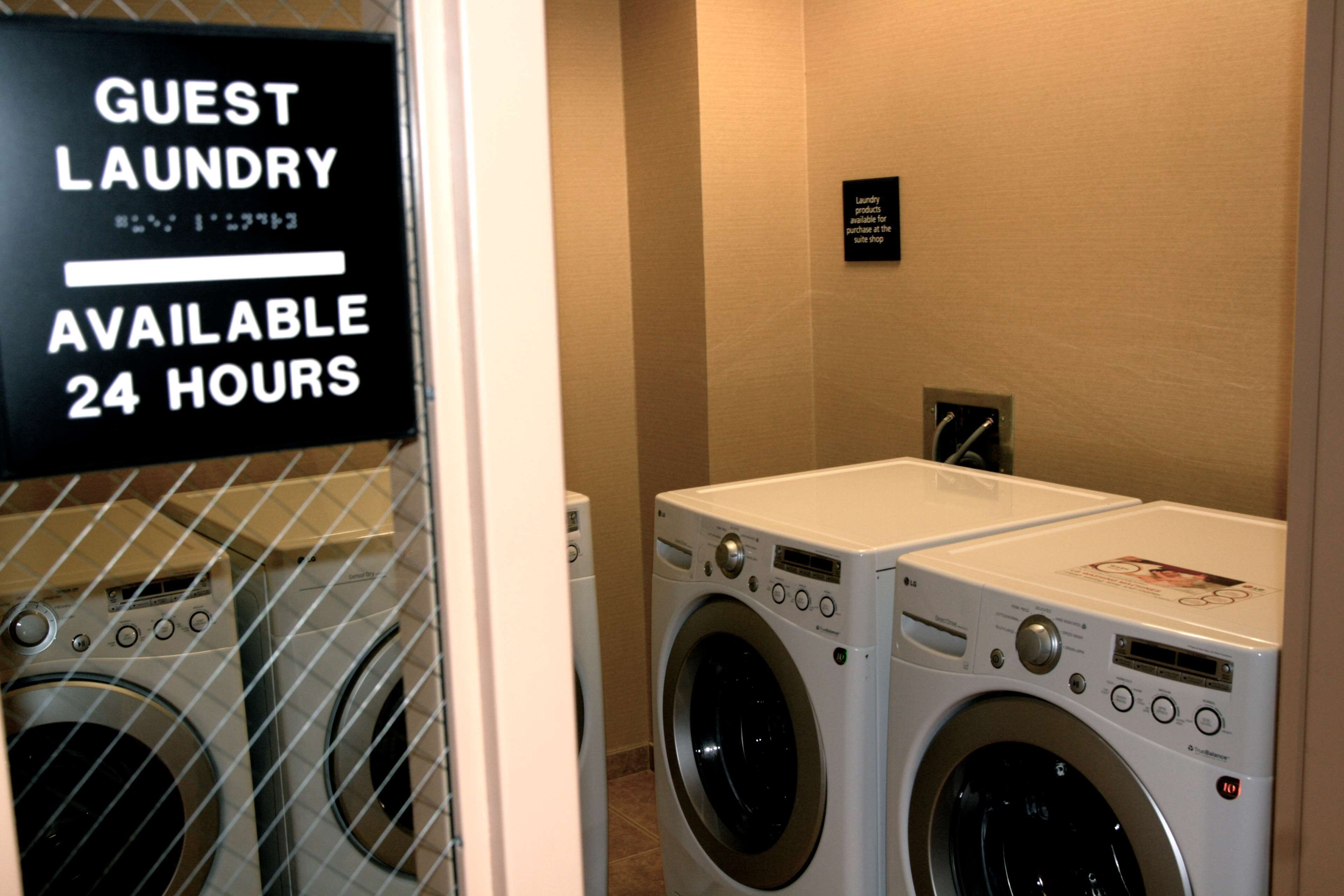A laundry area with a sign indicating guest laundry is available 24 hours.