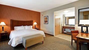 Ein Hotelzimmer mit Bett, Nachttischen, Schreibtisch, Stuhl, Spiegel und einer Badezimmertür.
