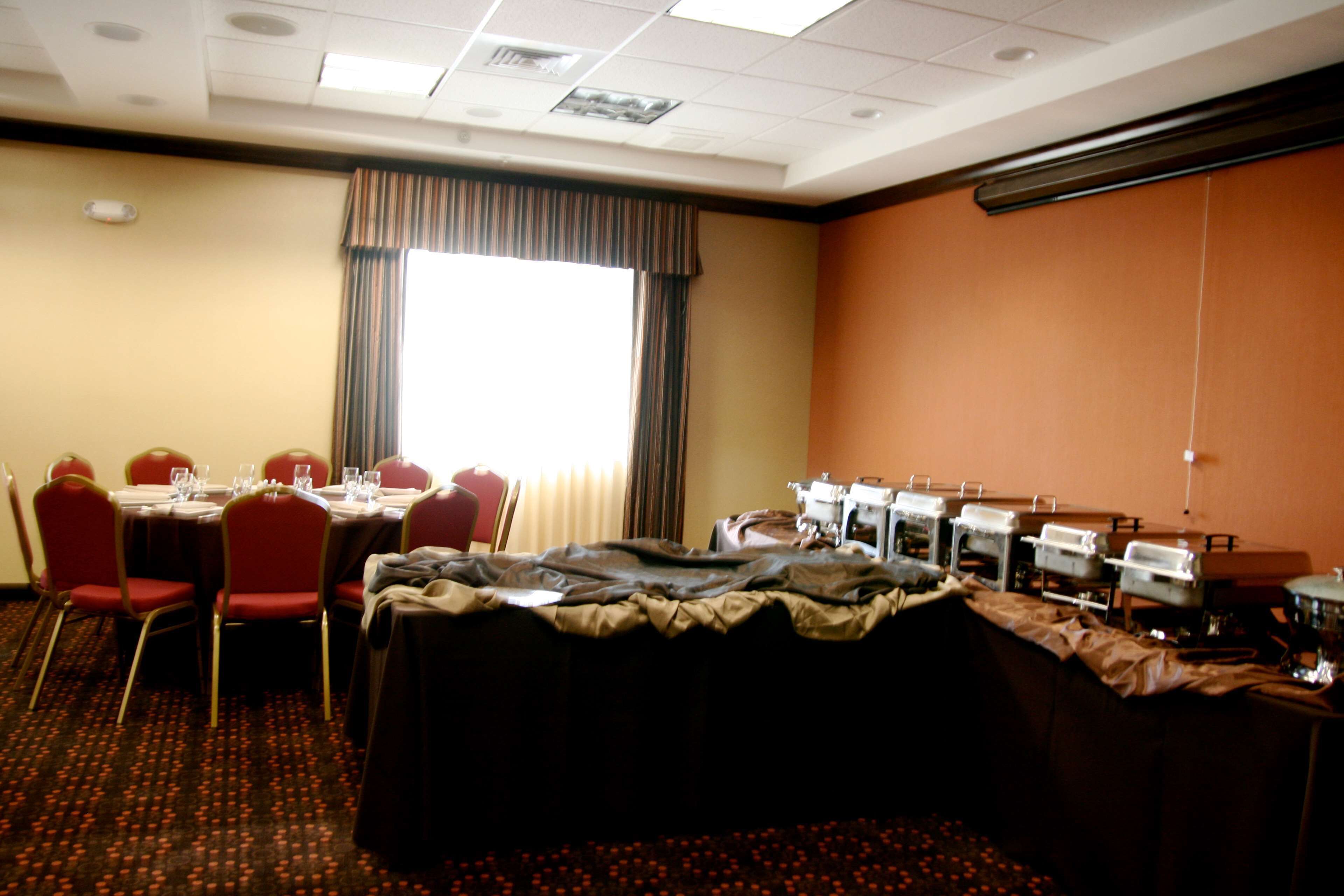 Sala de conferência com mesas, cadeiras e um buffet.