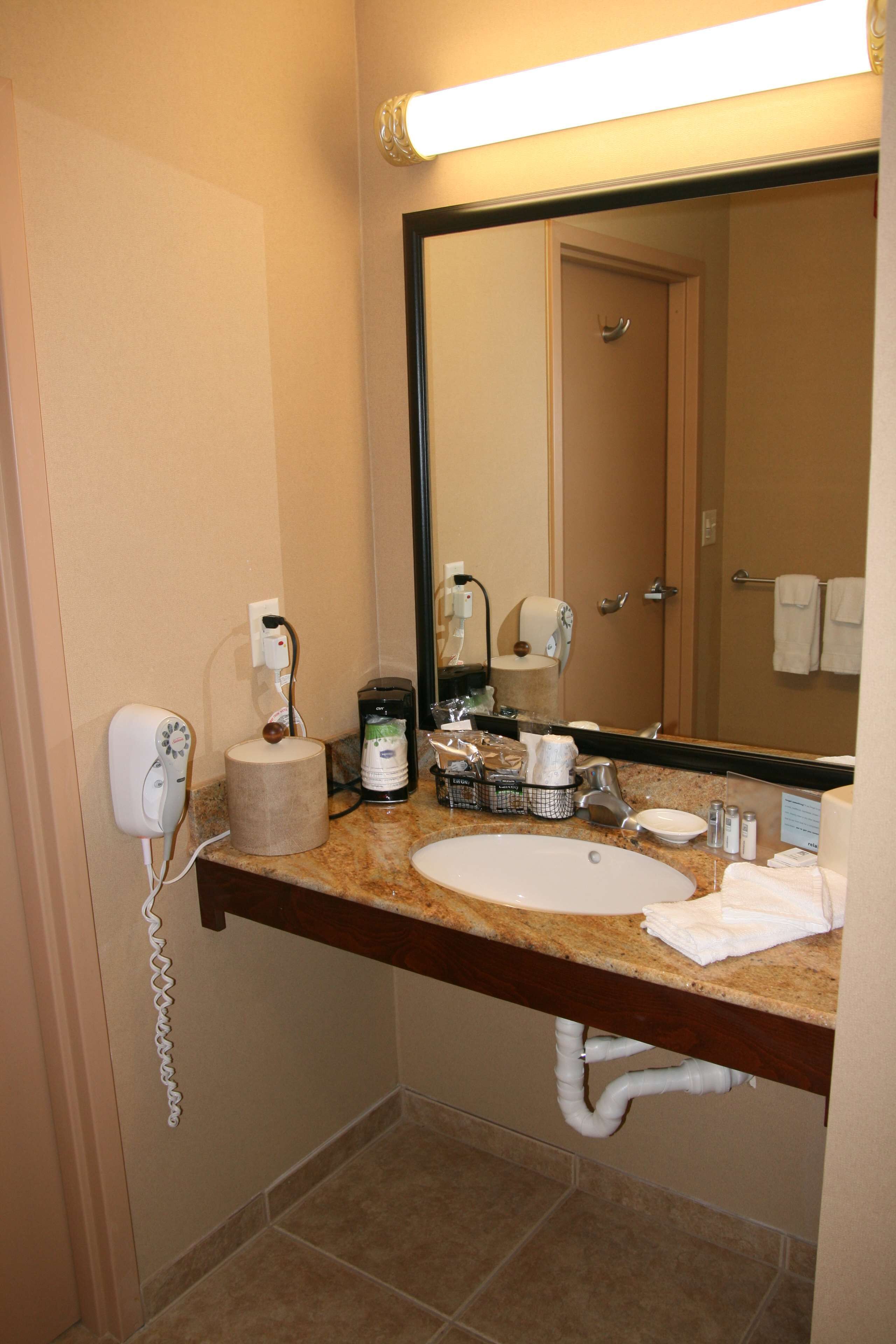 A hotel bathroom with a sink, mirror, towel rack, and a phone on the wall.