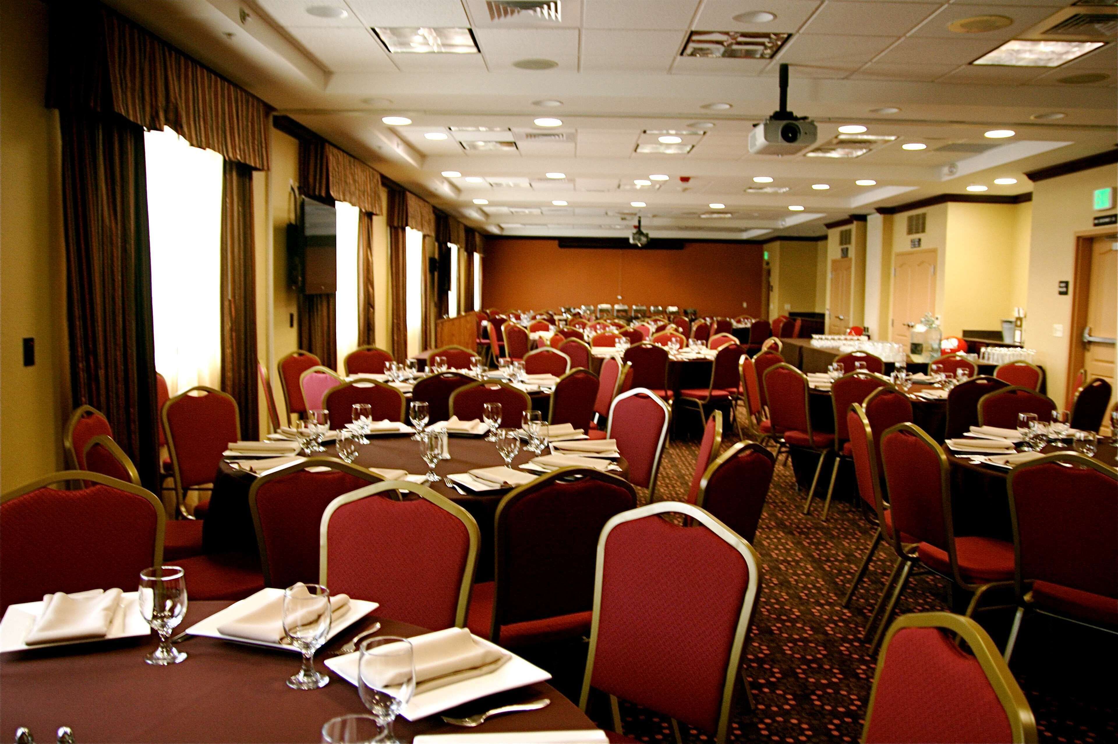 Une salle de conférence dotée de plusieurs tables et chaises, ainsi que de plaques nominatives et de verres.