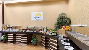 Un espace buffet agrémenté d’une pancarte indiquant « Petit-déjeuner Daybreak », avec différents stands de nourriture et une plante.