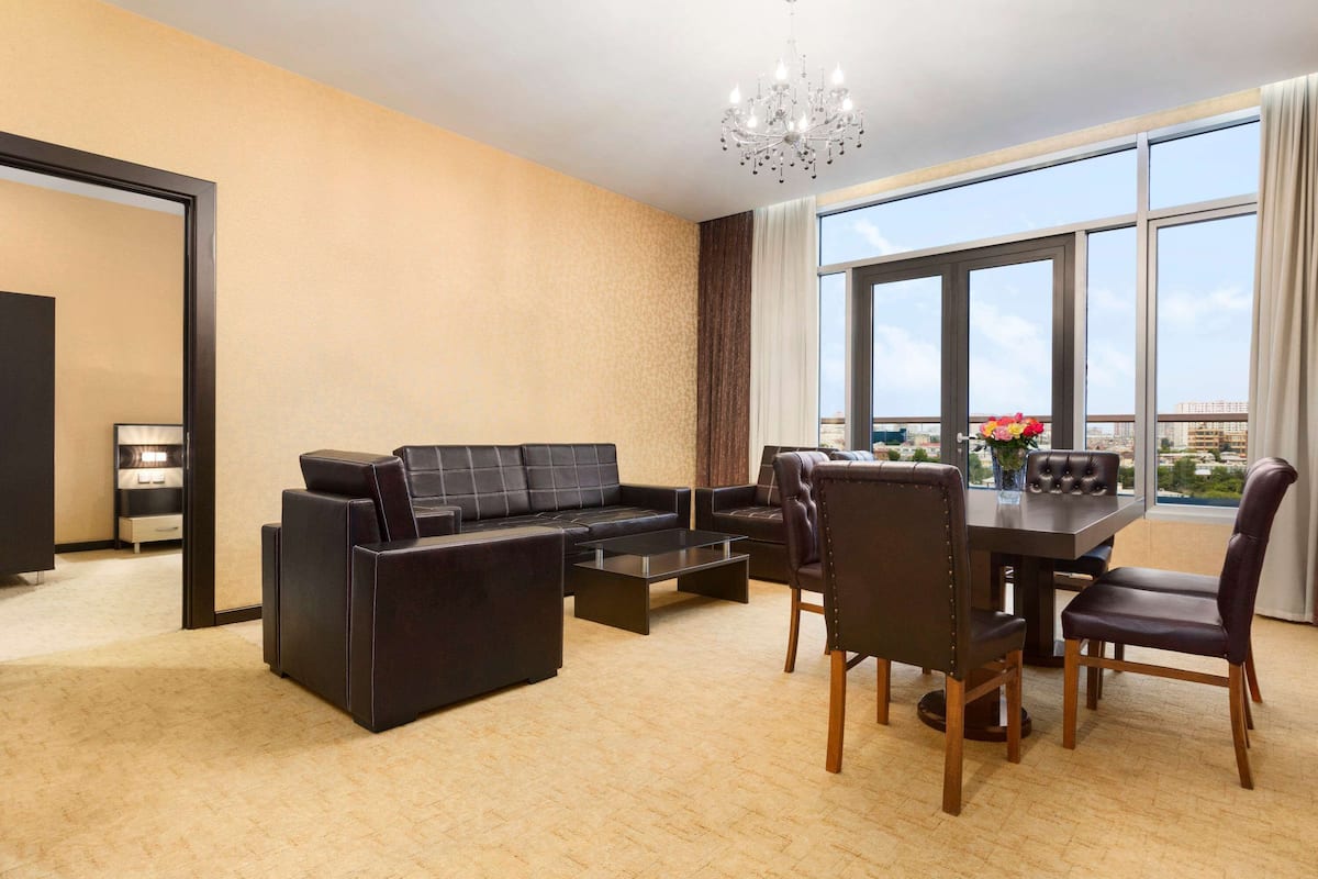 Ein modernes Wohnzimmer mit Sofa, Couchtisch, Esstisch und Stühlen. Eine Kristallleuchter, große Fenster und Blick auf die Stadt sind ebenfalls vorhanden.