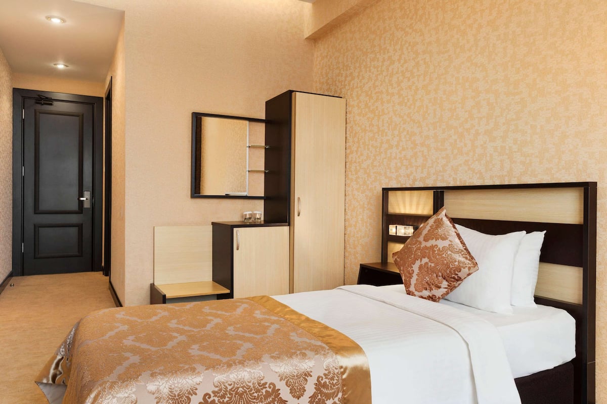 Ein Hotelzimmer mit Bett, Schrank, Schreibtisch und Spiegel.