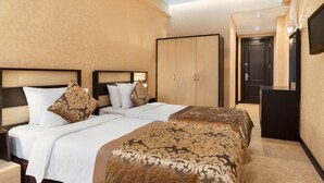 Ein Hotelzimmer mit zwei Betten, einem Kleiderschrank, einem Schreibtisch und einem Fernseher.